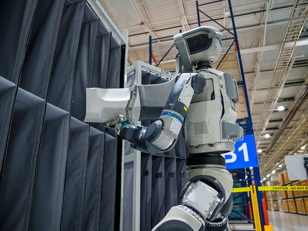 Atlas handling a white tote at a conveyor